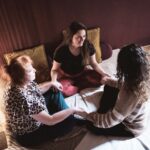 Lächelnde Teilnehmer:innen halten Händchen bei der Kuschelparty im KuschelRaum – Freude, Verbindung und achtsame Nähe erleben.