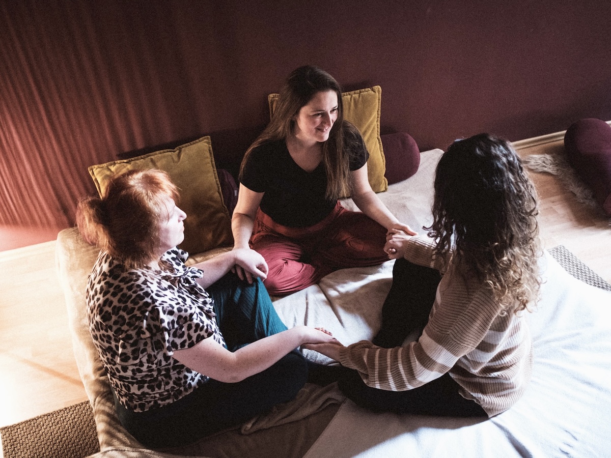 Lächelnde Teilnehmer:innen halten Händchen bei der Kuschelparty im KuschelRaum – Freude, Verbindung und achtsame Nähe erleben.